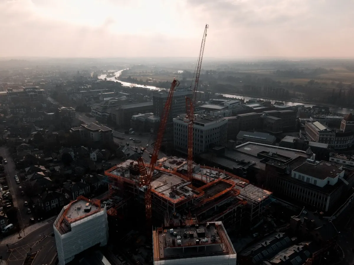 Chantier de construction vu par drone — immeuble en cours de gros œuvre avec grues, vue aérienne d'ensemble